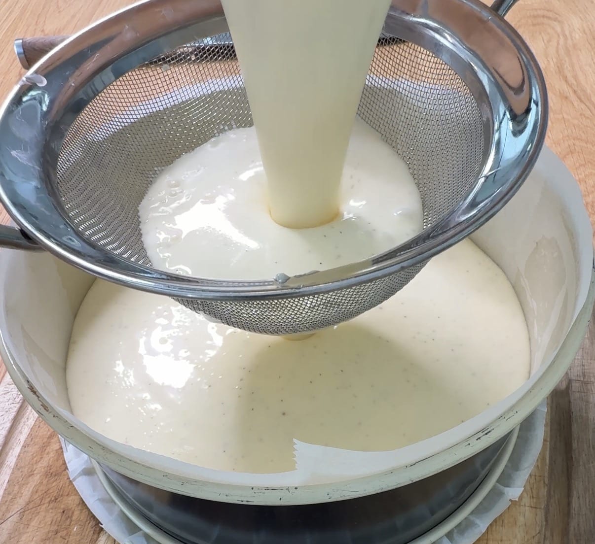 Ostemassen til cheesecake sigtes i en kageform